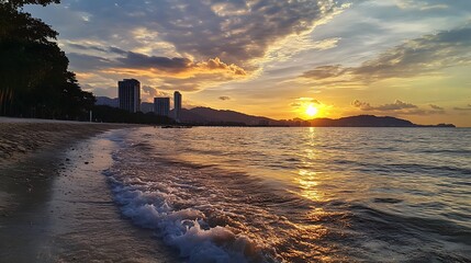 Sunset over a beach town.  Waves gently lapping on the shore, with a beautiful sunset over the ocean and cityscape in the distance