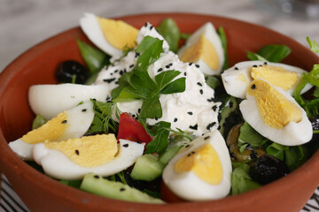 Fresh salad with eggs and herbs in a rustic bowl on a table