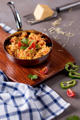 Shakshuka, eggs cooked in a tomato sauce garnished with coriander served in a metal pan on a wooden board side view of Middle Eastern breakfast dish