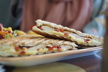 Delicious sandwich with chicken and cheese served in a cozy cafe