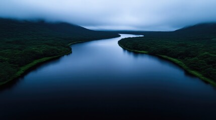 Obraz premium Serene river winding through misty mountains