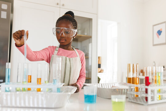 African American girl conducting science experiment with test tubes at home