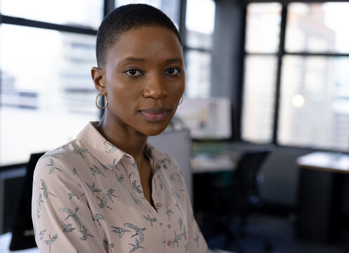Confident professional woman standing in modern office, looking at camera