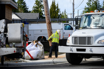 Temporary wood powerline pole cut off and being lifted out of place by utility digger derrick truck...