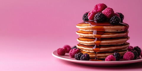 Fototapeta premium Golden pancakes with fresh raspberries and blackberries,with syrup on bright pink background for food blogs,restaurant menus or content related to breakfast and sweets.
