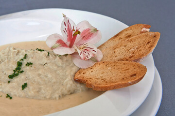 Creamy mushroom soup with slices of crusty bread adorned with a flower, vegan food