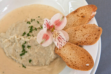Creamy mushroom soup with slices of crusty bread adorned with a flower, vegan food