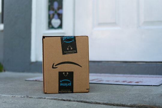Cardboard box with Amazon Prime label dropped off on home porch. Ordered online Christmas gift in package on doormat. Priority delivery of purchased online products. Sarasota, USA - December 19, 2022.