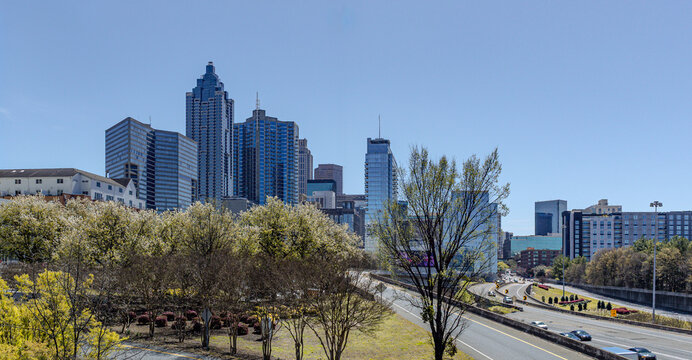 Downtown Atlanta Skyline showing several prominent buildings, highways, cars and hotels under a blue sky.