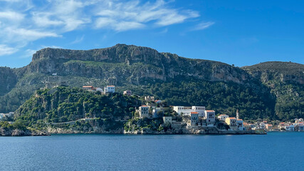 Coastal Village On A Rocky Hill With Traditional Houses, Greek Flag Flying, Surrounded By Green Mountains And Blue Sea, Summer Vacation Spot, Scenic Landscape, Ideal For Travel And Tourism.