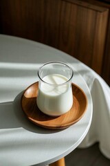 there is a glass of milk on a wooden plate on a table