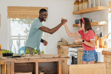 Celebrating successful gardening project, Diverse couple sharing joyful moment in cozy kitchen