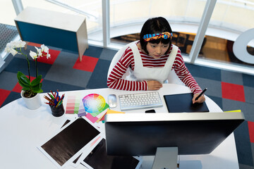 Asian woman using graphic tablet and computer, designing in modern office, copy space