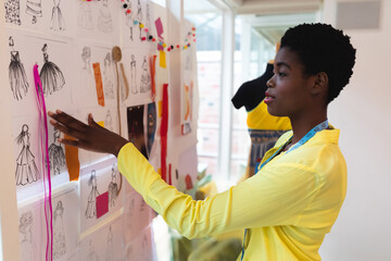 Fashion designer reviewing sketches on inspiration board in modern studio, copy space