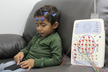 EEG electroencephalogram of a 3-year-old Latino boy with cables and electrodes attached to the head...