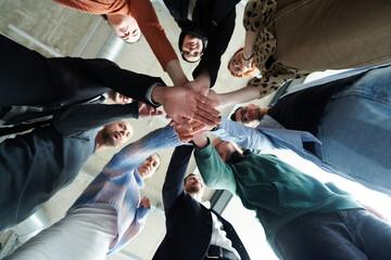 A group of business professionals, captured from a low angle, holding hands to symbolize unity and teamwork.