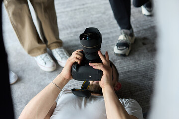 A photographer lies on the floor, capturing a heartfelt shot of a group of models embracing each other, showcasing their natural connection and joy in an intimate and creative moment