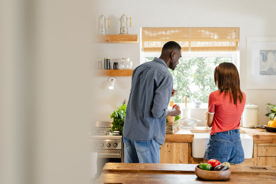 Diverse couple preparing meal together in cozy kitchen, enjoying vacation time