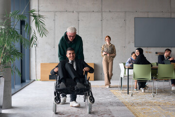 Employee Entertaining Director in a Wheelchair While Rolling Through the Office with Laughter and...