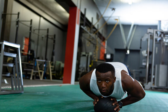Athletic man in gym doing push-ups on medicine ball, focused and determined, copy space