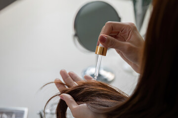 Hair Care and Beauty Routine. Applying hair serum for healthy and radiant locks.