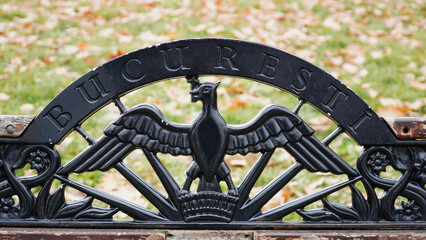 Ornate bench featuring Bucarest inscription and eagle design set in a lush park during autumn