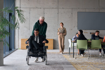 A diverse team of business colleagues, including a director in a wheelchair, engages in a collaborative discussion as they move together through a modern office space