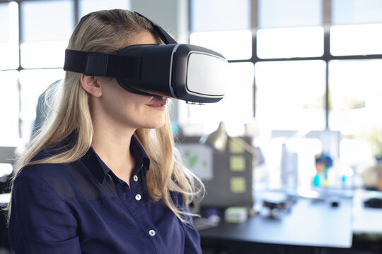 Woman using VR headset in modern office, exploring virtual reality technology