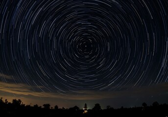 Rotating Star Trails Above Landscape Silhouette at Night Time