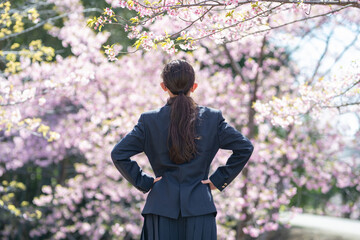 桜の前に立つ制服を着た女子生徒