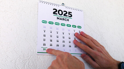 Close-up of a male hand pointing finger at Eid al-Fitr date 2025 on a wall calendar