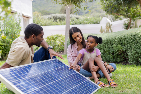 Family exploring solar panel technology together in sunny backyard garden
