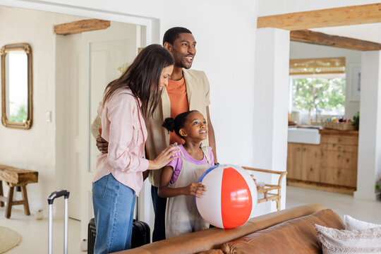 African American family with beach ball smiling and preparing for vacation at home