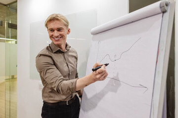 Smiling businessman drawing growing graph on flip chart during presentation
