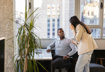 Businesswoman interrupting businessman wearing headphones in office