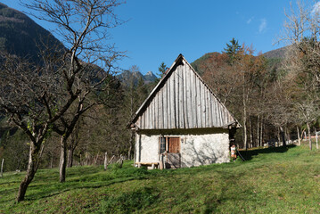 Old wooden farmhouse nestled in a tranquil mountain valley in autumn