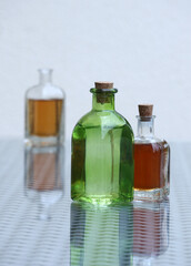 Still life with three vintage bottles with different aromatic oils on a glass top table. Soft selective focus. Space for your text.