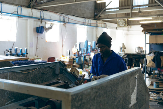 Crafting sports equipment, African American man working diligently in workshop, focused