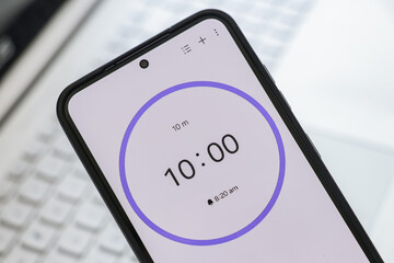 A phone with a black and white 10-minute timer to study with pomodoro method on laptop keyboard,...