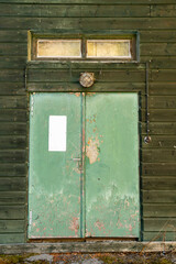 Old shabby door of a wooden building with a retro lamp.