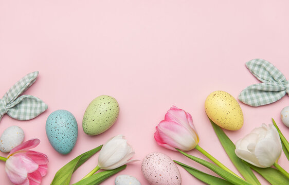 Easter eggs and tulips creating a frame on pink background