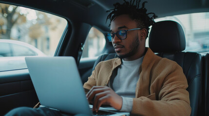 Businessperson sitting in the backseat of a rideshare car and working on a laptop