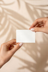 Obraz premium Close up of a Well Manicured Hand Holding a Blank Card Against a Soft Background With Interesting Shadows