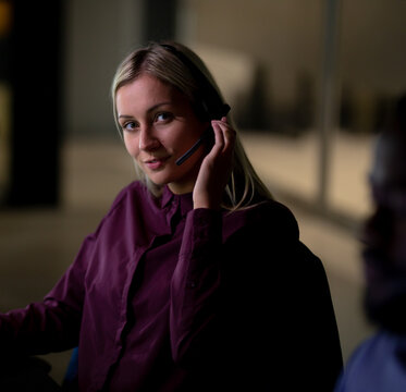 Using headset, customer service representative assisting clients during late-night shift