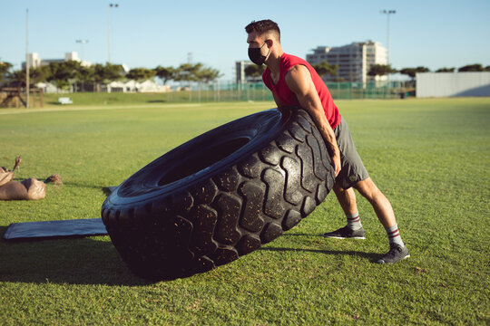 Man flipping large tire outdoors, building strength and endurance in workout - Powered by Adobe