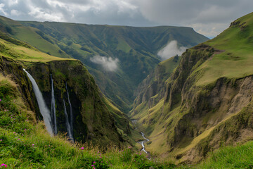 Majestic waterfall cascading down steep green cliffs within a breathtaking mountain valley, clouds drift across the landscape.