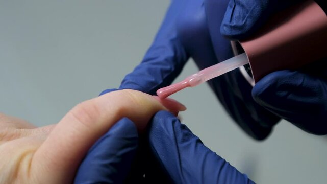 Selfmade manicure service. Manicurist paints nails with pink gel polish. Nail polish application. Manicured pink nails. High quality 4k footage