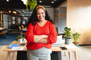 Confident woman in office standing with arms crossed, smiling at camera