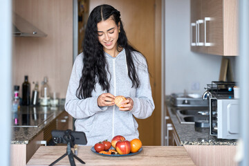 Food blogger recording a video peeling a tangerine in a kitchen