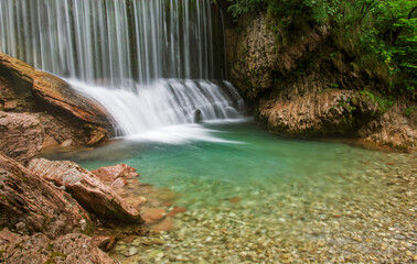 a waterfall in the forest with the water of Spring